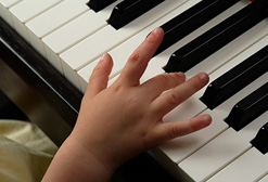 Toddler hand and piano keyboard.