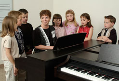 Teacher at piano with young students.